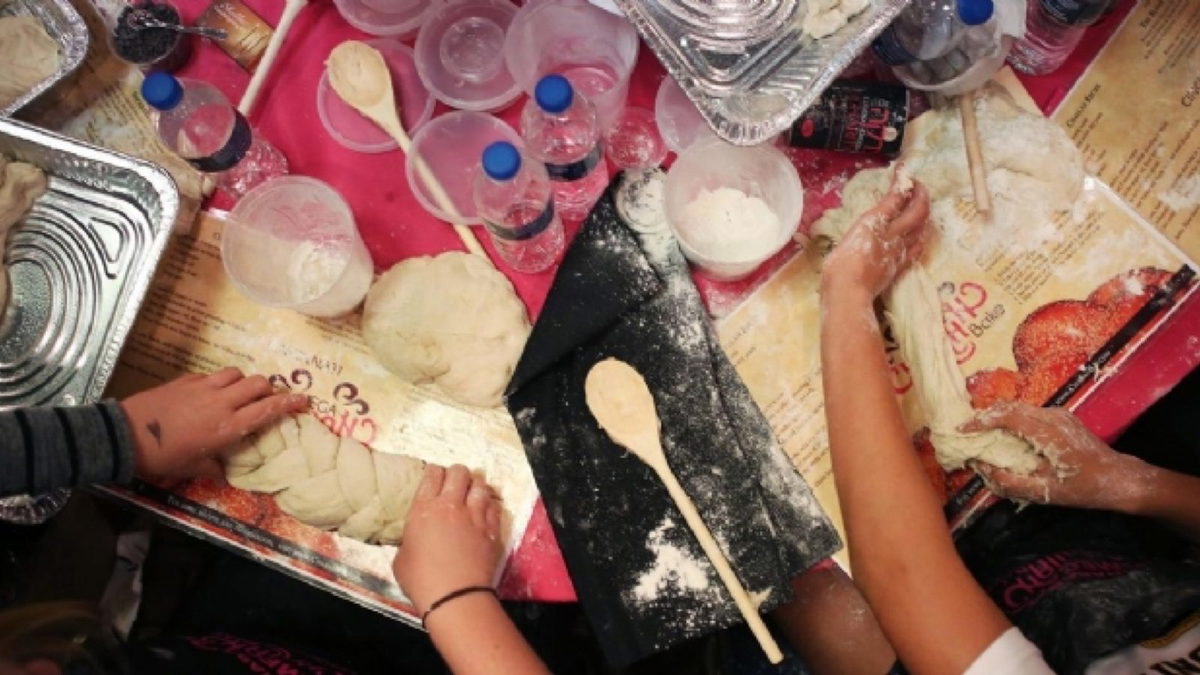 Women's floured hands braiding challah dough on the bake mats