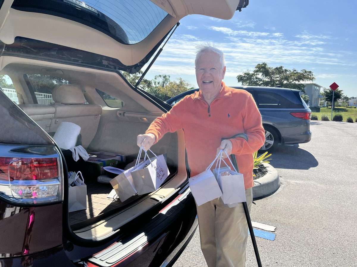 A volunteer lifting bagged challahs out of a car trunk to deliver them