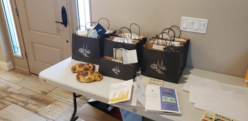 Shabbat Shalom gift bags and fresh braided challah arranged on the welcome table