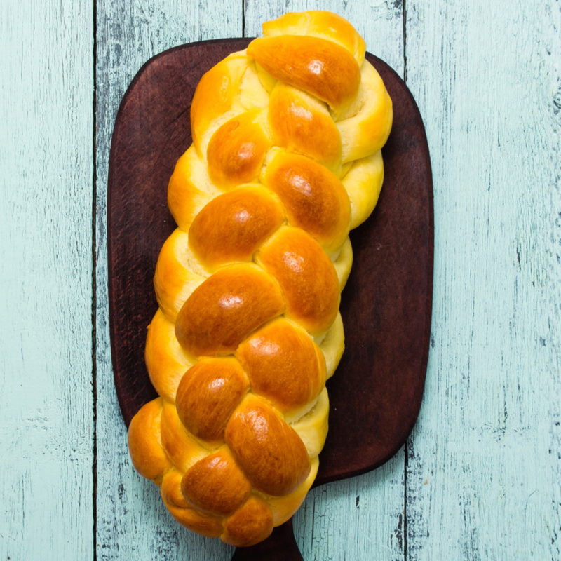 Freshly baked braided challah on a wooden board
