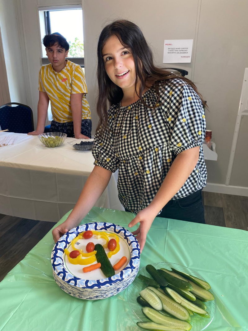 A teen presenting her smiley-face veggie plate at a CTeen event